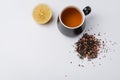 Fruit tea in a black mug, lemon segment and dried tea isolated on white background. Top view and copyspace