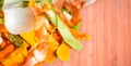 Fruit and vegetable peels of different colors on the wooden table surface