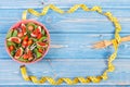 Fruit and vegetable salad, fork with tape measure, slimming and nutrition concept, copy space for text on boards Royalty Free Stock Photo