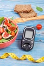 Fruit and vegetable salad and glucometer with tape measure, concept of diabetes, slimming and healthy nutrition Royalty Free Stock Photo