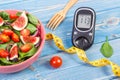 Fruit and vegetable salad and glucometer with tape measure, concept of diabetes, slimming and healthy nutrition Royalty Free Stock Photo