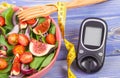 Fruit and vegetable salad, glucose meter for measurement sugar level and tape measure, concept of diabetes Royalty Free Stock Photo