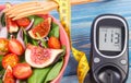 Fruit and vegetable salad and glucose meter with tape measure, diabetes, slimming and healthy nutrition concept Royalty Free Stock Photo