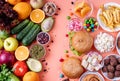 Fruit and vegetables vs sweets and fast food top view flat lay on orange background