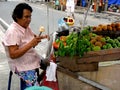 Fruit vendor selling green mangoes and cotton fruit at a sidewalk