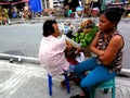 Fruit vendor selling green mangoes and cotton fruit at a sidewalk