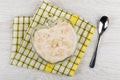 Fruit yogurt with oat bran in bowl on napkin, spoon