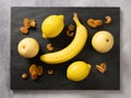 Fruits background yellow color composition on dark stone slake plate and light table. Summer abstract creative trendy fresh health