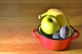 fruits, banana, apple, plum in a red metallic pot with copy space