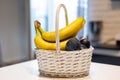 White basket with bananas and plums