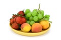 Fruits and berries are on a wooden plate. Apricots, strawberries and green grapes