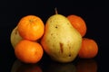 Fruits on black background. four tangerines and pear on a black background.