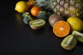 Fruits on black background - pineaple, tangerine, orange, citrus fruits, kiwi, broccoli. Healthy food, lose weigh. Copy space.