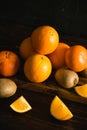 Fruits on a dark background. Oranges and kiwi on a wooden cutting board