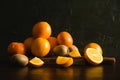 Fruits on a dark background. Oranges and kiwi on a wooden cutting board