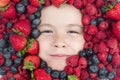 Fruits for kids. Assorted mix of strawberry, blueberry, raspberry, blackberry background. Berries closeup near kids face Royalty Free Stock Photo