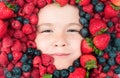 Fruits for kids. Assorted mix of strawberry, blueberry, raspberry, blackberry background. Berries closeup near kids face Royalty Free Stock Photo