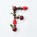 Fruits pattern of letter F english alphabet from natural ripe berries - black currant, cherries, raspberry, mint leaf Royalty Free Stock Photo