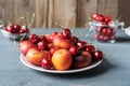 Fruits on the plate, sieve and glass jar. Grey wooden table Royalty Free Stock Photo