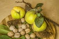 Fruits of quince with faded leaves, a handful of walnuts in shell, coniferous cones, on kitchen board