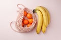 Fruits tangerine, banana in recycling net market bag on white background. String mesh bag, minial concept, recycle idea