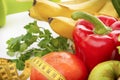 Fruits and vegetables with dumbbells and measuring tape on a white background, healthy food, peppers, bananas, Apple, greens, Royalty Free Stock Photo