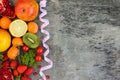 Fruits, vegetables and in measure tape in diet on wooden background