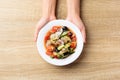 Fruits and vegetables spicy salad on plate holding by hand Royalty Free Stock Photo