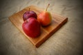 Fruits on a wooden cutting board - two red apples and a pear