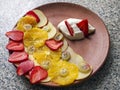 Fruity carpaccio made from apples, orange, strawberry and gooseberry. Fruit dessert with whipped cream on a clay plate