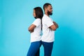 Black couple standing back to back, blue studio wall Royalty Free Stock Photo