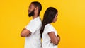 Black couple standing back to back, yellow studio wall Royalty Free Stock Photo