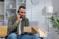 A frustrated African American young man at home talks on the phone with the delivery service, solves problems with the Royalty Free Stock Photo