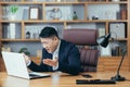 Frustrated and angry asian businessman working on laptop in office, boss shouting at laptop screen Royalty Free Stock Photo