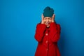 Frustrated angry dark-haired woman in bright red coat and warm green hat cries, screams, holding her head, expressing negative Royalty Free Stock Photo