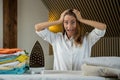 Frustrated angry young woman holding her head and screaming near the ironing board at home Royalty Free Stock Photo