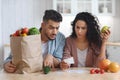 Frustrated Arab Spouses Sitting In Kitchen Checking Bills After Grocery Shopping Royalty Free Stock Photo
