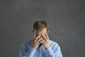 Frustrated ashamed desperate man hiding his face in his hands on grey studio background Royalty Free Stock Photo