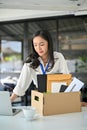 Frustrated Asian female office employee packing her belongings at her desk, quitting job Royalty Free Stock Photo