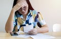 Frustrated Asian woman holding and looking at bills and calculating her monthly expenses and debts at house Royalty Free Stock Photo