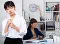 Frustrated asian woman standing at office