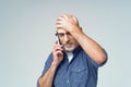 Frustrated bald middle aged man tired or having headache talking on the phone isolated on white background. Handsome man Royalty Free Stock Photo