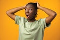 Frustrated beautiful African American female feels anxious and surprised, yellow studio