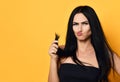 Frustrated beautiful brunette woman examining looking at her dry damaged hair over yellow background. Health And Beauty Concept Royalty Free Stock Photo