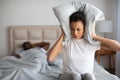 frustrated black girlfriend covering ears disturbed by husband& x27;s snoring indoors