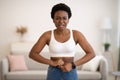 Frustrated Black Woman Buttoning Small Jeans After Weight Gain Indoors Royalty Free Stock Photo