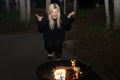 Frustrated blonde young adult woman pleads with her campfire to start burning. Taken at night Royalty Free Stock Photo