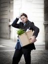 Frustrated business man on street fired carrying cardboard box Royalty Free Stock Photo