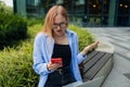 Frustrated business woman received bad news in e-mail on mobile phone while sits outside company near copy space Royalty Free Stock Photo