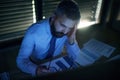 Frustrated businessman with computer sitting at desk, working late. Financial crisis concept. Royalty Free Stock Photo